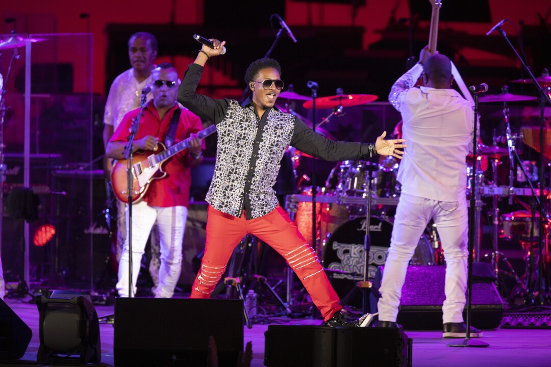 A man holding a microphone moves across the stage.