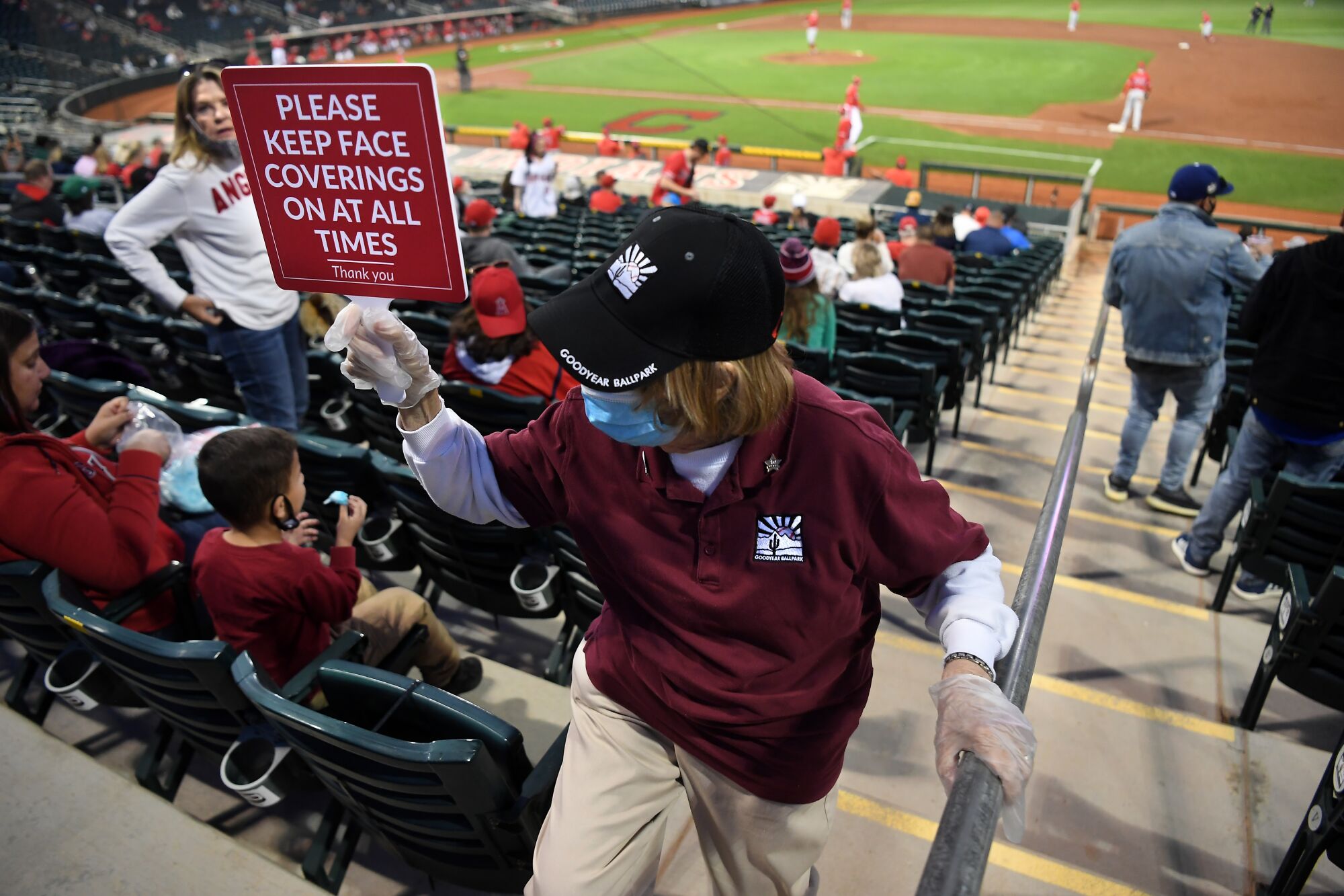 An usher carries a sign to remind fans to wear their masks