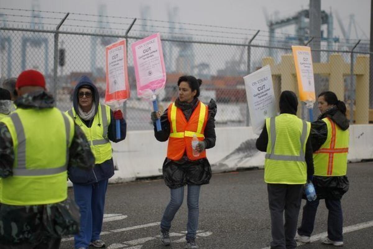 Striking workers carry pickets outside the APM Terminal at the Port of Los Angeles. Talks aimed at resolving the 5-day-old strike were continuing on Saturday.