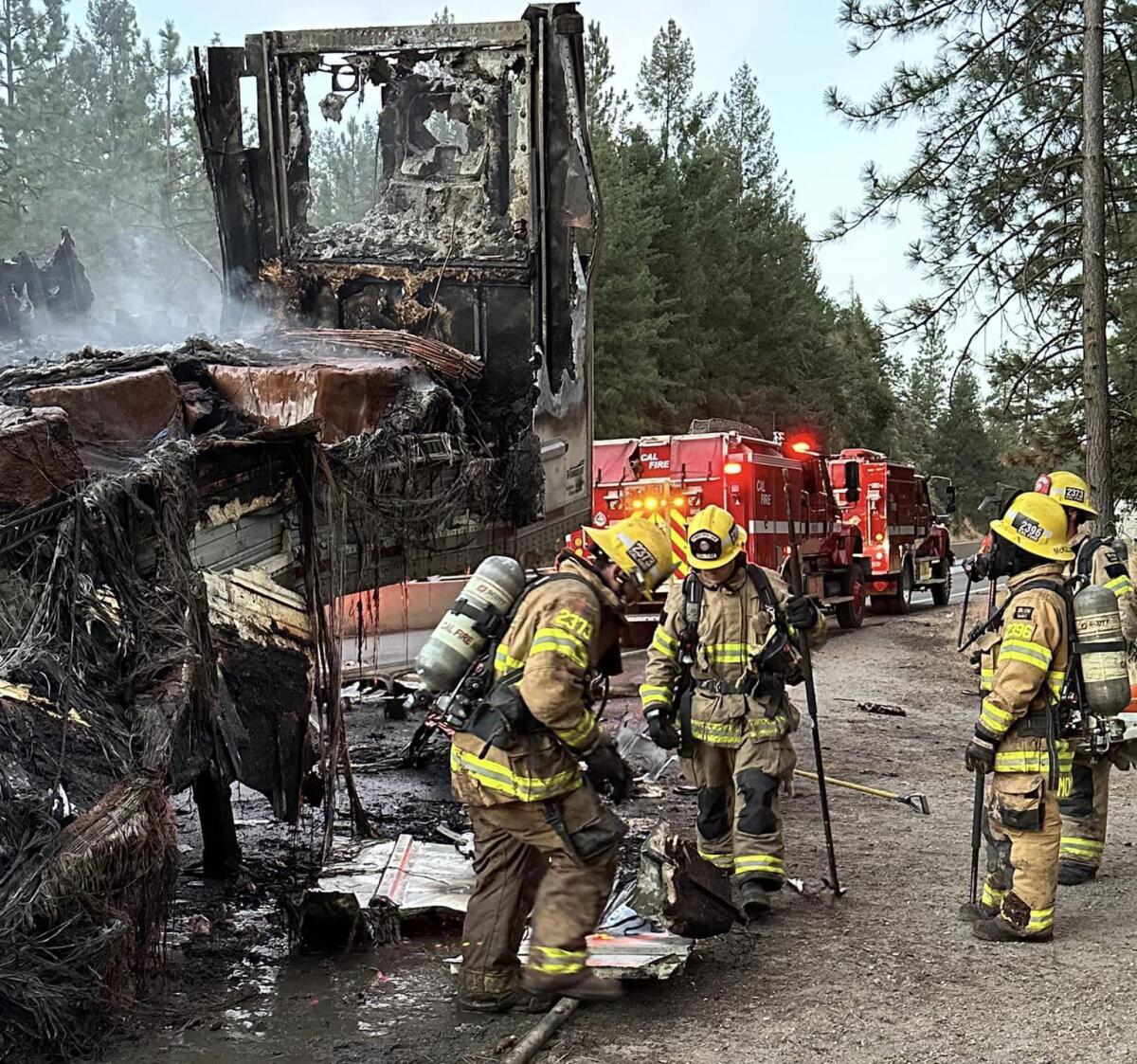 Firefighters surround a burned semi truck.