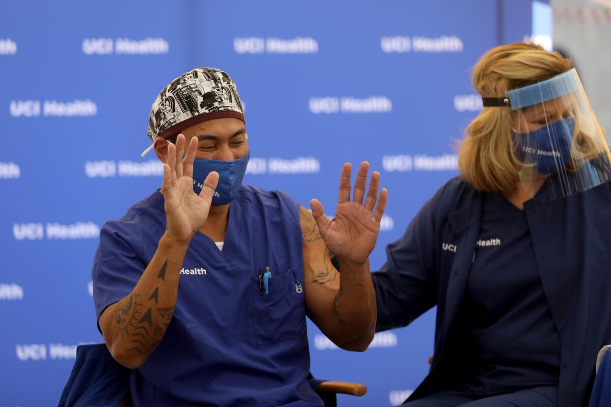 Erik Mara puts his hands up after receiving the Pfizer-BioNTech COVID-19 vaccine from registered nurse Pam Samuelson.