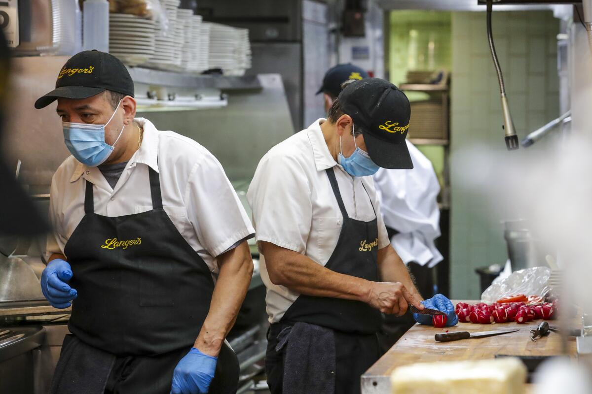 Masking-wearing employees prep food at Langer's Delicatessen-Restaurant