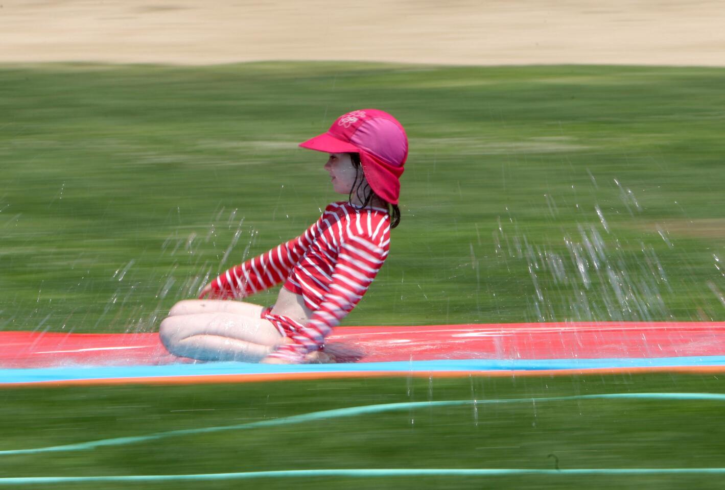 Camp Runamuk participant Ava Blair slides along a slippery wet slide during water play at the Community Center of La Cañada Flintridge in La Cañada Flintridge on Tuesday, June 21, 2016. Children had wet activities for about one hour.
