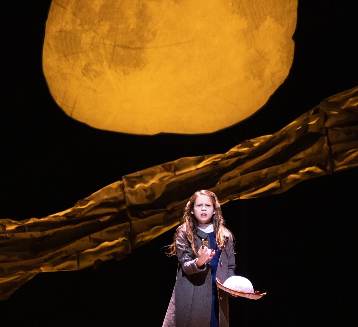 A girl stands under the abstract depiction of the sun in "The Secret Garden" at Center Theatre Group's Ahmanson Theatre. 