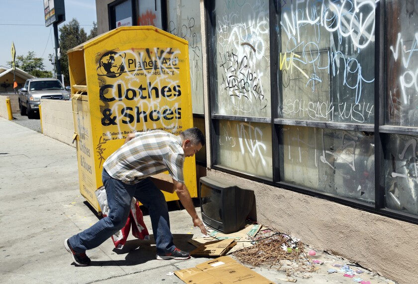 Gonzalo Ponce, owner of Ponce's Bakery in East Los Angeles, picks up garbage near a Planet Aid donation bin earlier this month.