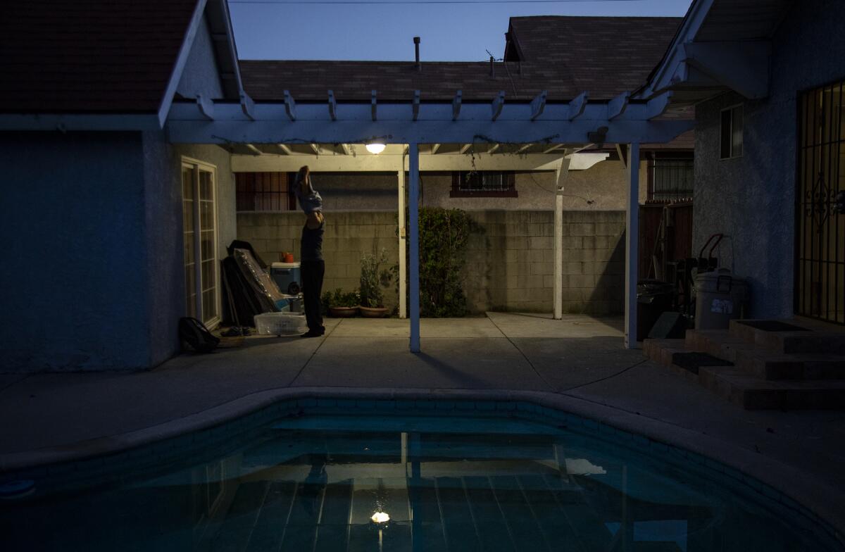 Nurse Justin Foronda takes off his work clothes in the backyard before entering the house. 