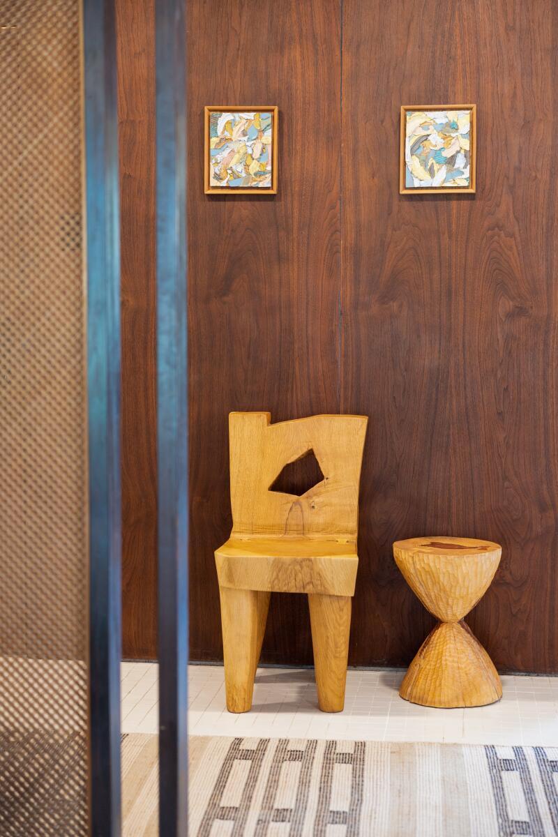 A wood chair and stool against a darker wood wall