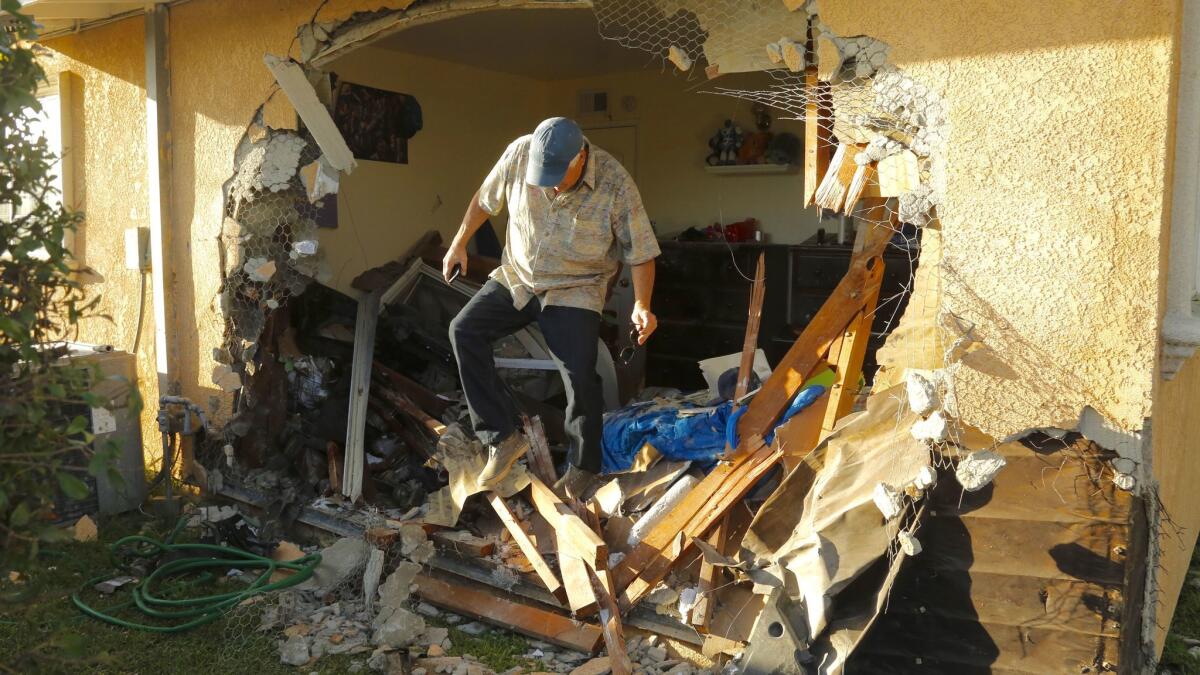 City of La Puente building inspector Jim Jurekovic steps through the hole left in the home owned by Antonio Perez after a car smashed into a front bedroom of the home on Duff Ave in La Puente Wednesday morning.