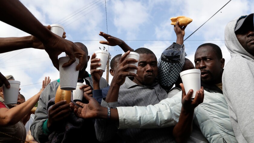Haitian migrants receive food and drinks from volunteers as they wait Oct. 3 at a Mexican immigration agency in Tijuana with the hope of gaining an appointment to cross to the U.S. side of the border.