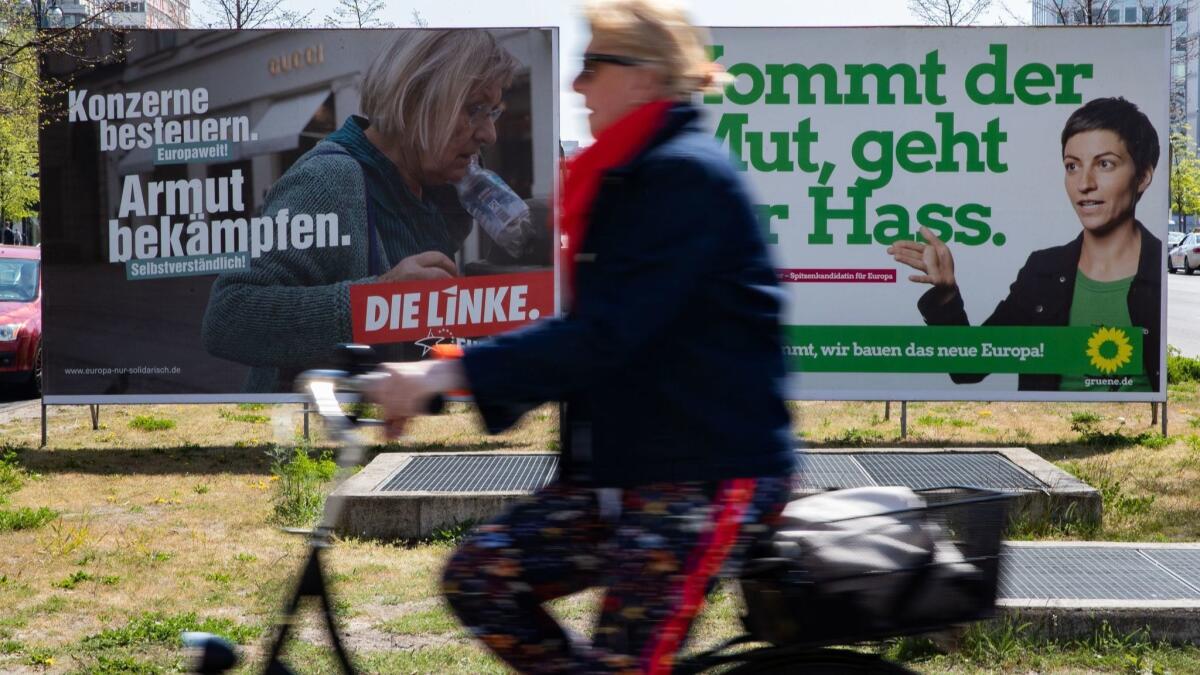 In a file photo from April 2019, a bicyclist in Berlin passes election campaign posters for the Left (die Linke) party and the Greens party (poster at right) during campaigning for the recent European Parliament elections.