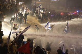 Policías israelíes emplean un cañón de agua para dispersar a los manifestantes que cortan una autopista durante una protesta contra los planes del primer ministro, Benjamin Netanyahu, de reformar el sistema judicial del país, en Tel Aviv, Israel, el lunes 27 de marzo de 2023. (AP Foto/Oren Ziv)