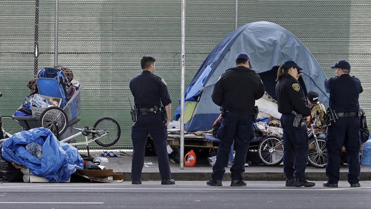 San Francisco police officers wait while homeless people collect their belongings in this 2016 file photo. San Francisco supervisors voted Tuesday to allow the city to force some people with serious mental illness and drug addiction into treatment.