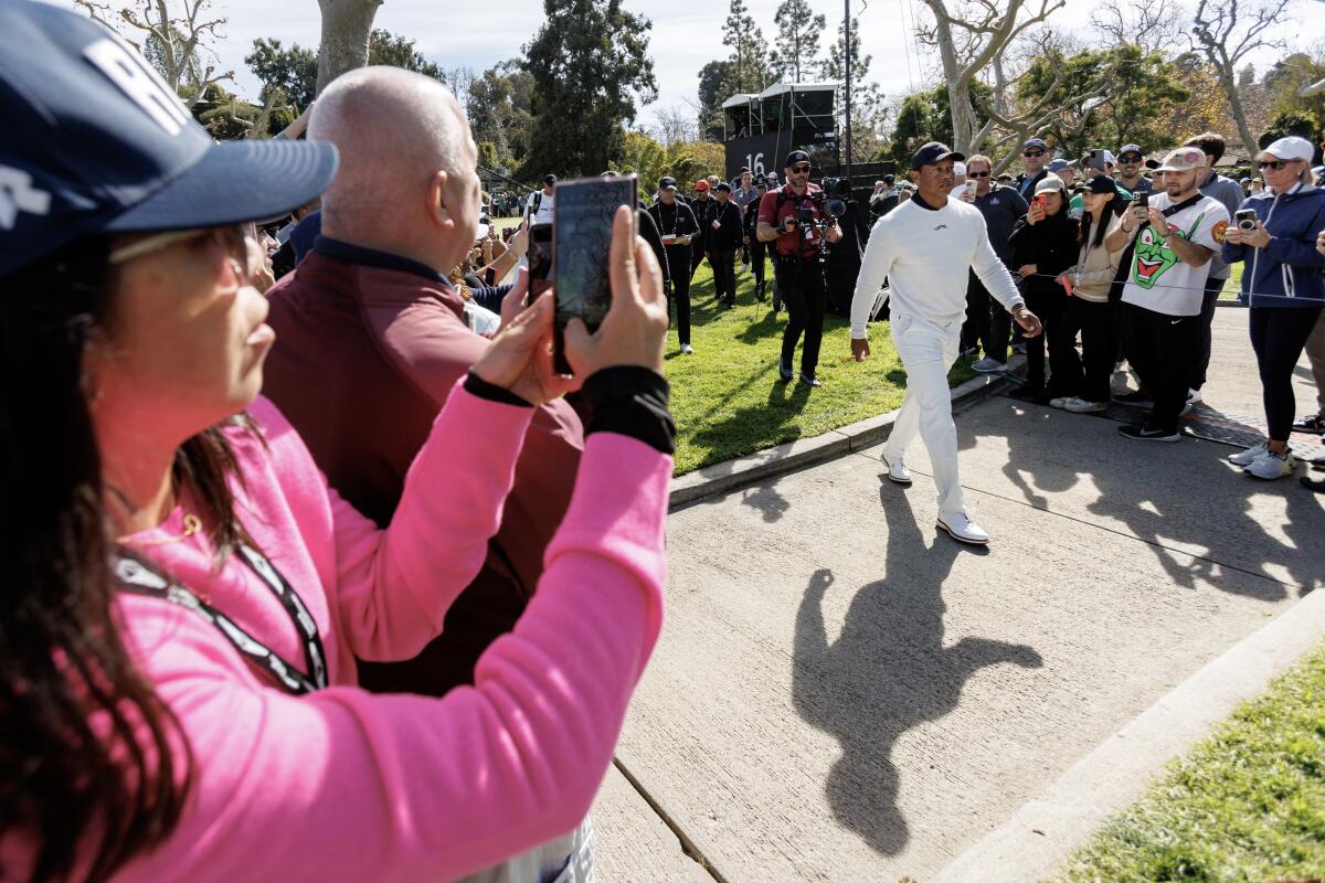 A fan snaps a photo as Tiger Woods walks to the 17th tee box.