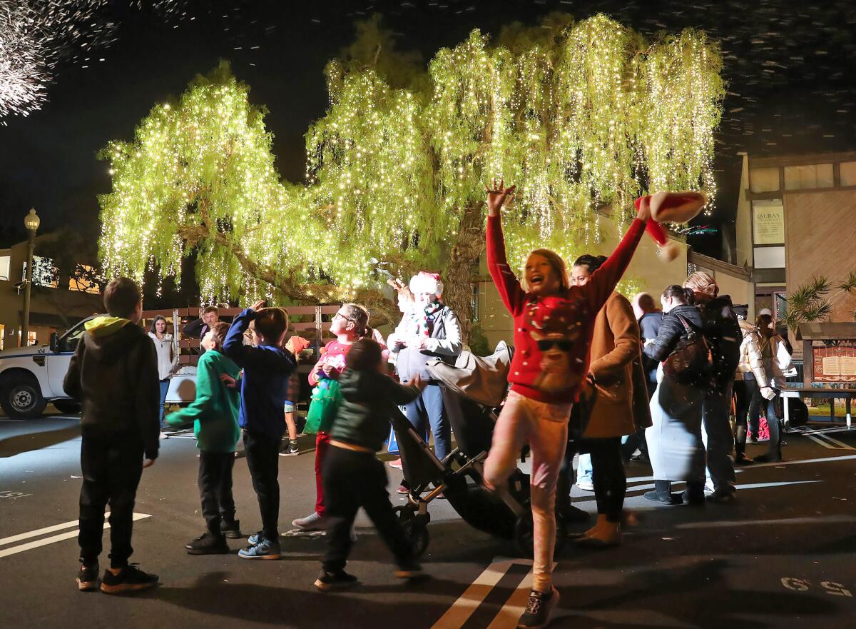 Kids and families play and dance near the Peppertree Lot's "Christmas Tree" during Hospitality Night in Laguna Beach.