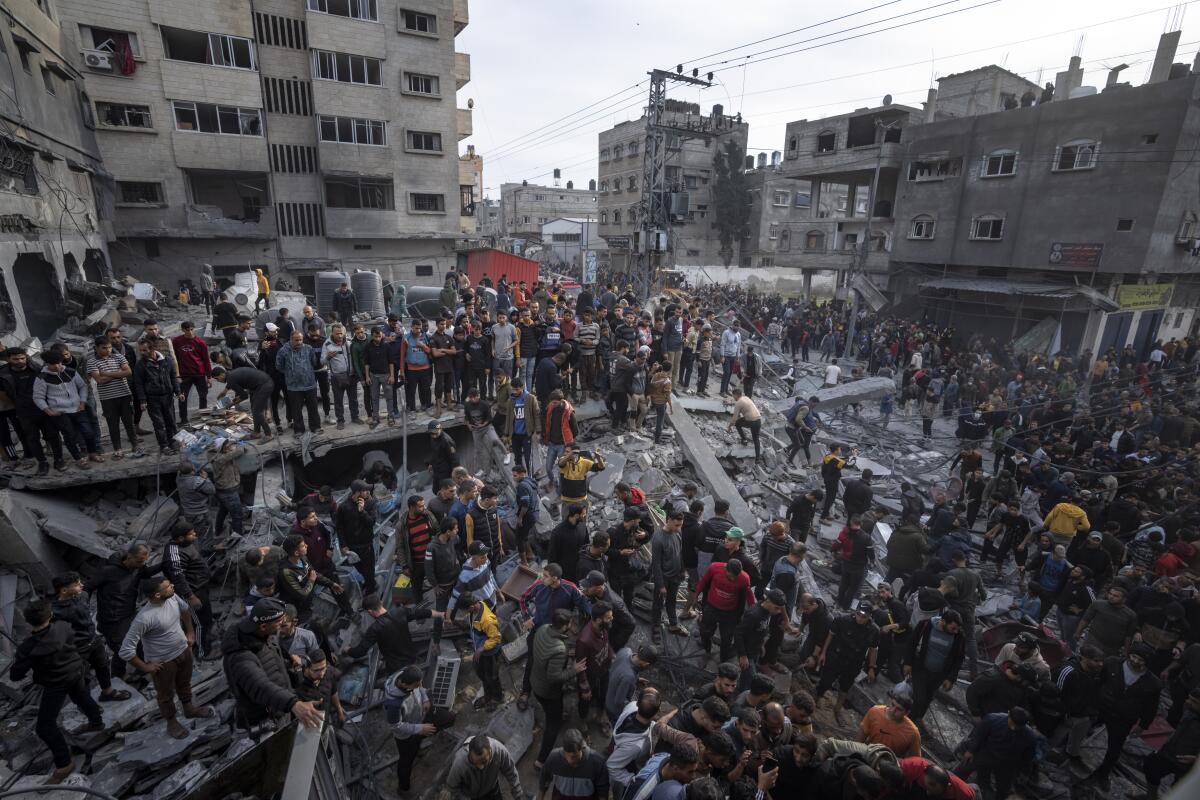 Palestinians search for bodies and survivors in the rubble of a residential building.