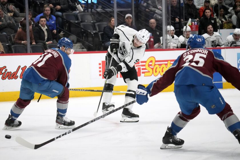 Los Angeles Kings right wing Adrian Kempe, center, fires the puck between Colorado Avalanche center Andrew Cogliano, left, and right wing Logan O'Connor in the second period of an NHL hockey game Thursday, March 9, 2023, in Denver. (AP Photo/David Zalubowski)