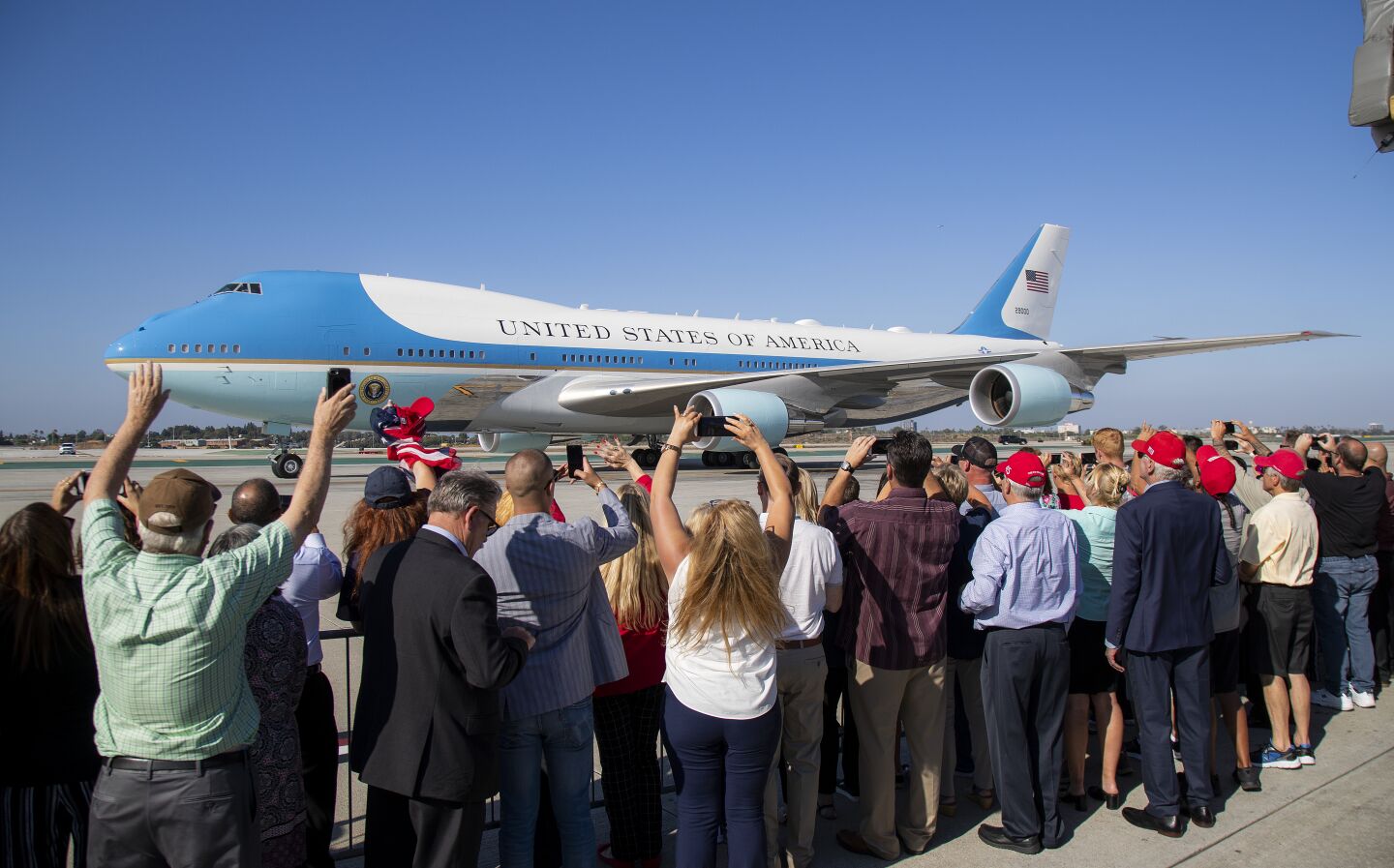 President Trump supporters wave as Air Force One taxies along the runway after landing at LAX.