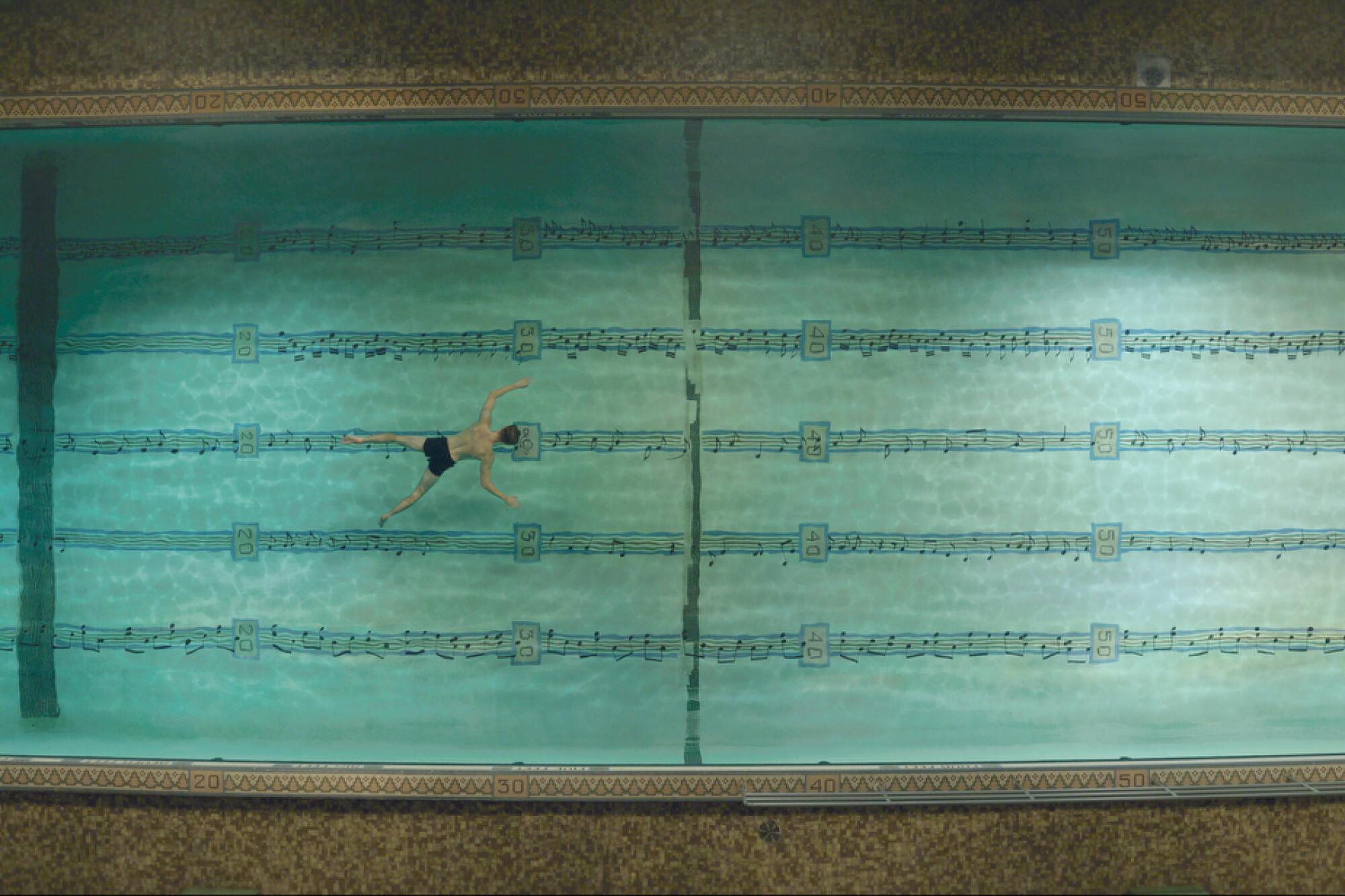 Andrew Garfield swims in a large pool with musical notes on the bottom in "Tick, Tick...Boom!"