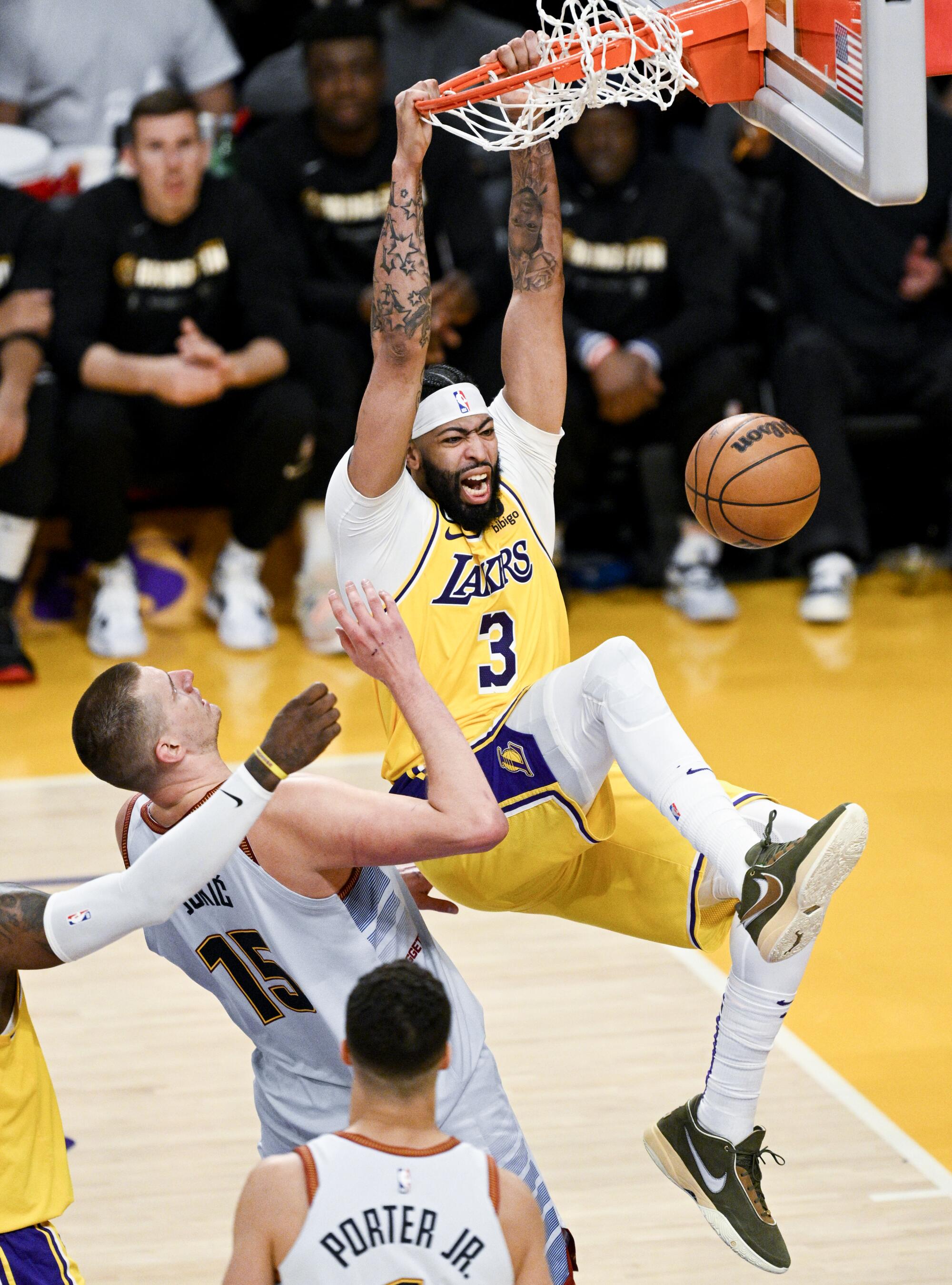Lakers forward Anthony Davis, right, dunks in front of Denver Nuggets center Nikola Jokic.