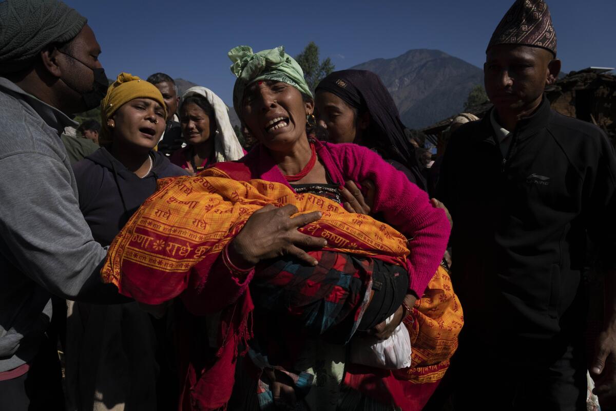 A crying woman holds the lifeless body of her grandchild killed in the earthquake in Nepal