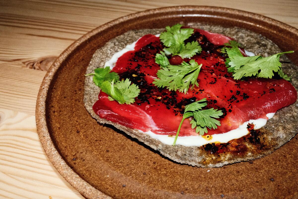 Tuna tostada with salsa negra and lemon aioli on a blue corn tortilla in ceramic plate at A Tí in Echo Park