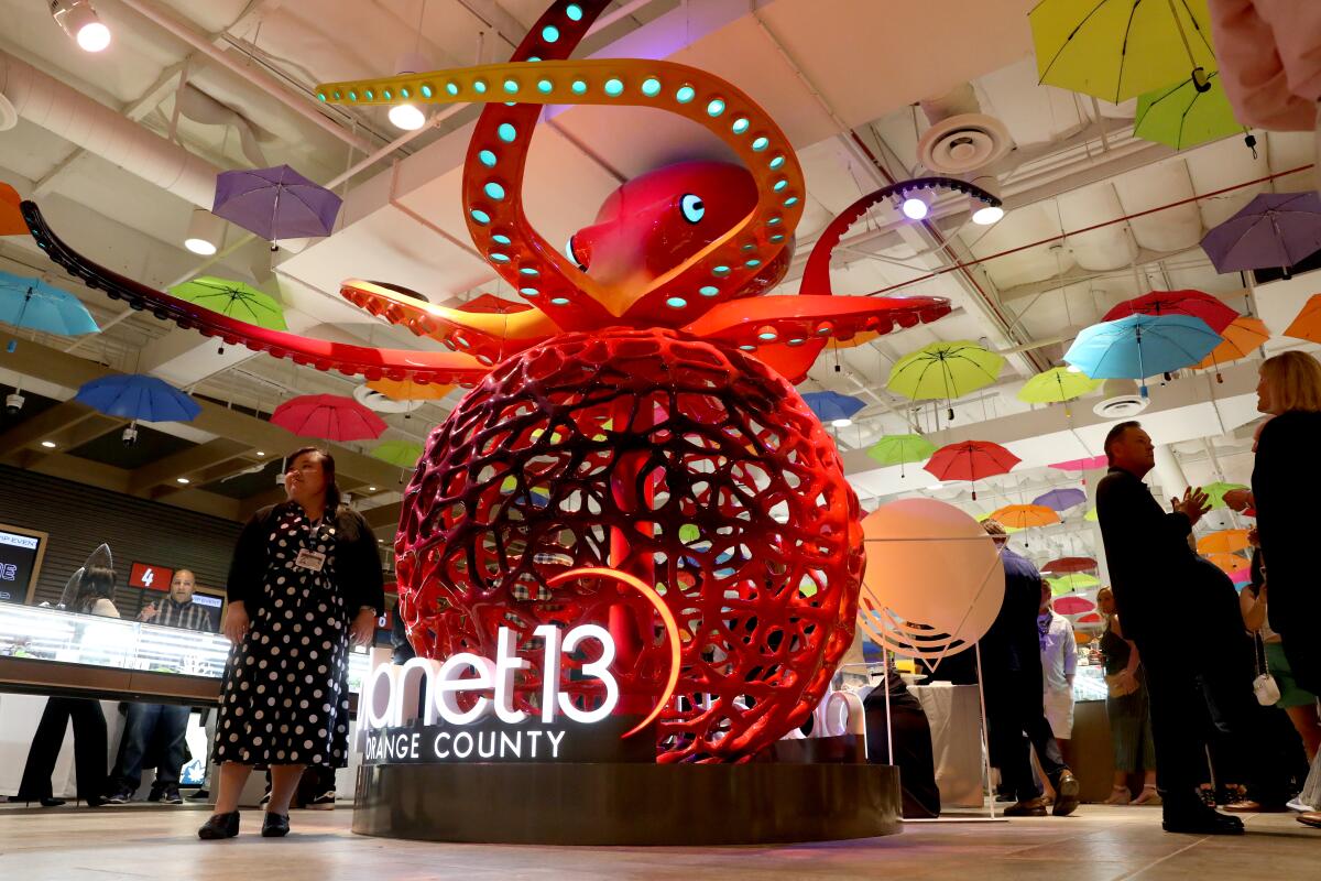 A woman stands next to a very large octopus sculpture.