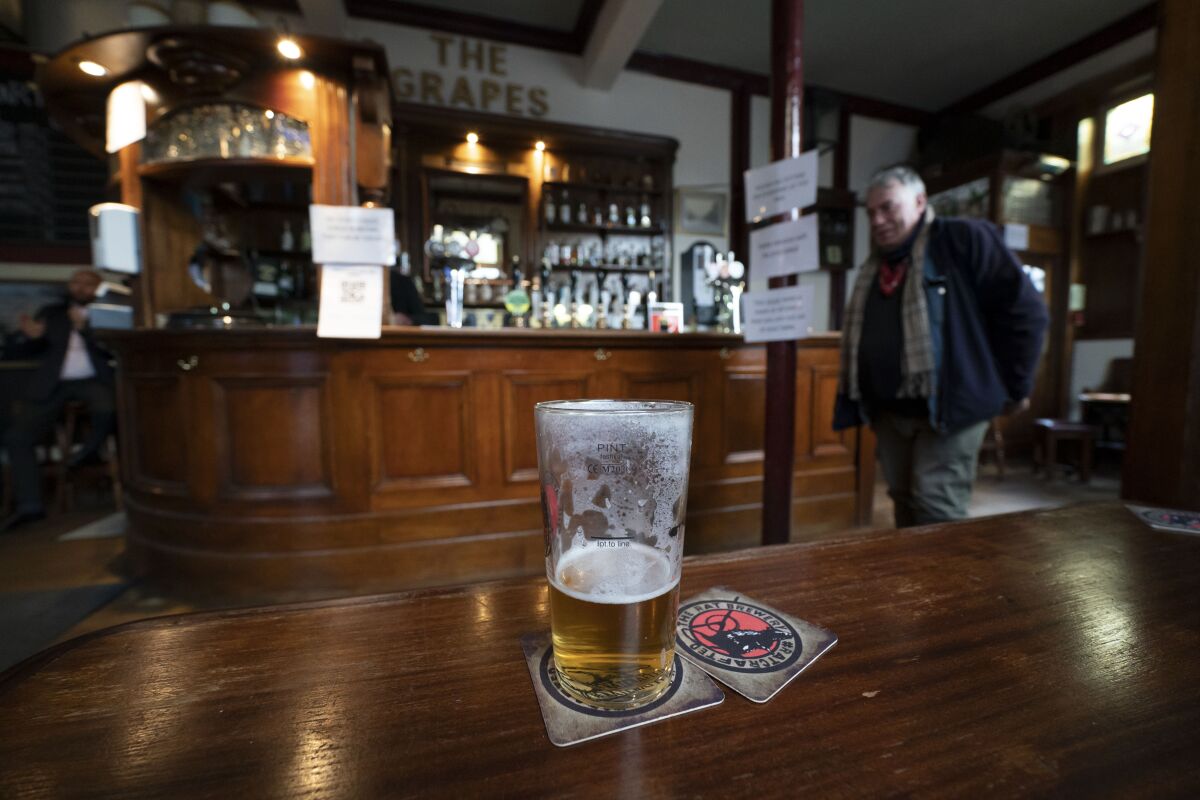 A view of a beer glass, at the Dispensary pub in Liverpool, England, Monday Oct 12, 2020. The British government has carved England into three tiers of risk in a bid to slow the spread of a resurgent coronavirus. The northern city of Liverpool is in the highest category and will close pubs, gyms and betting shops. (AP Photo/Jon Super)
