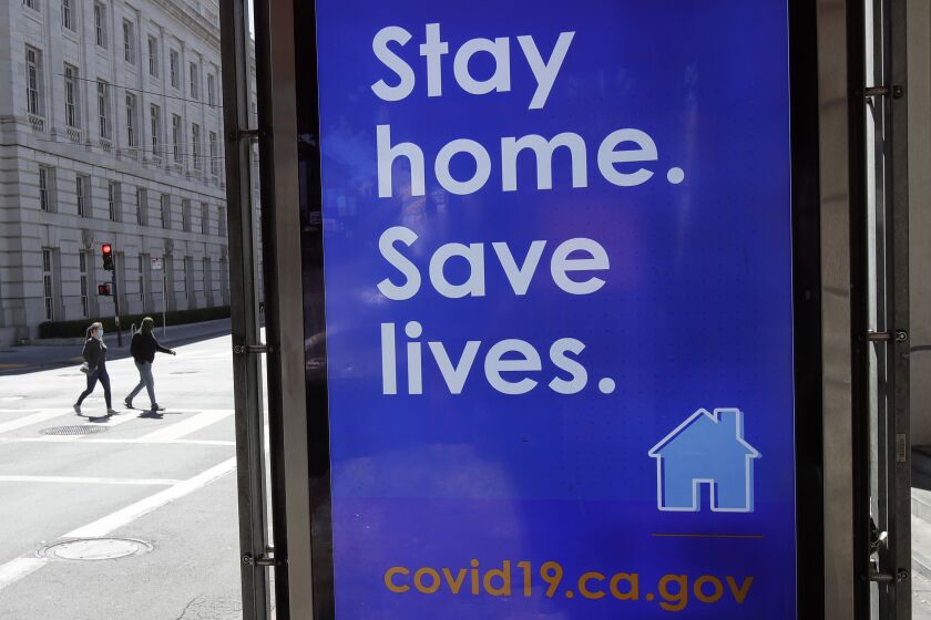 A sign advising people to stay home due to COVID-19 concerns is shown at a MUNI bus stop in San Francisco, Thursday, April 2, 2020. (AP Photo/Jeff Chiu)