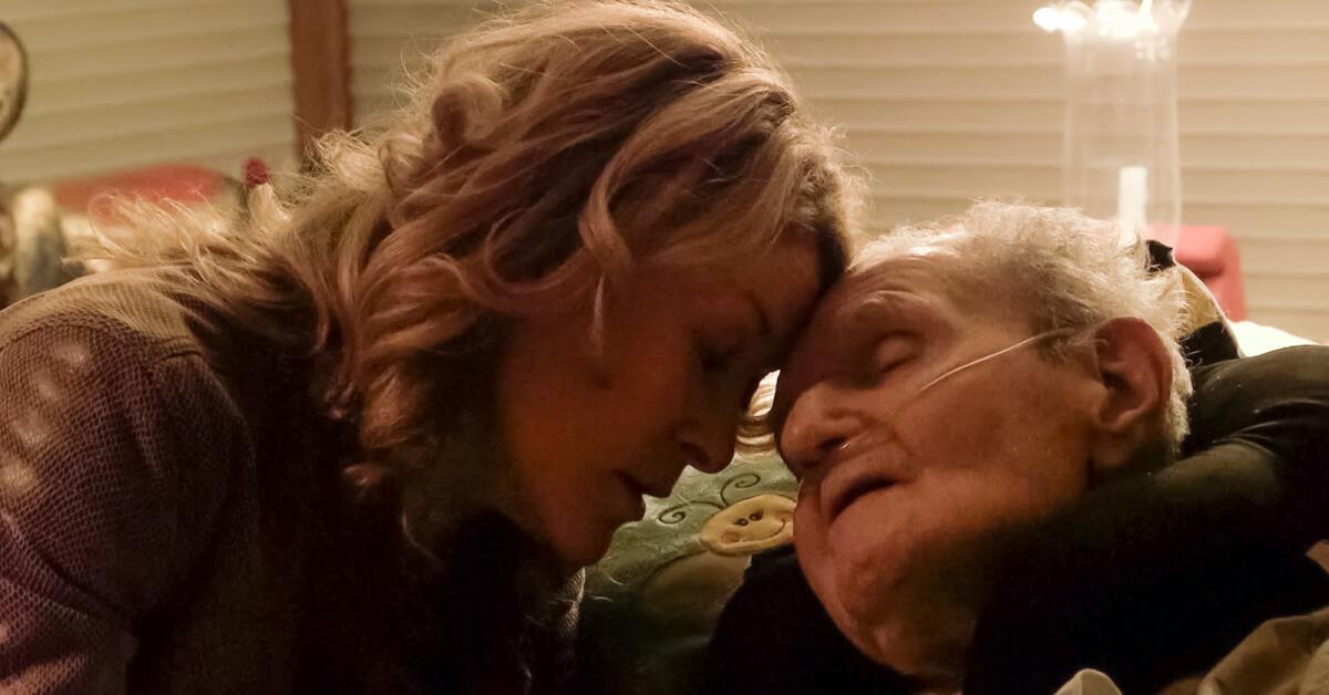 A woman touches her head to the forehead of an elderly man in the documentary "Last Flight Home."