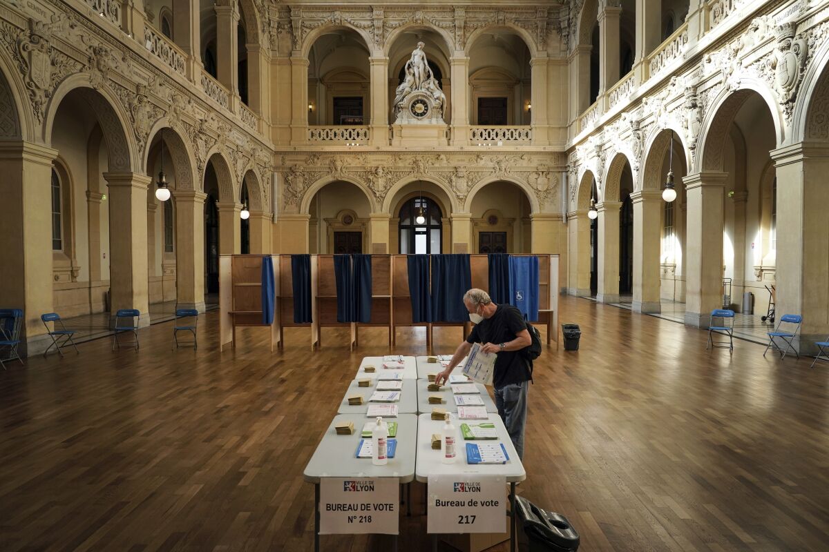 FILE - A voter picks up ballots before voting for the regional elections in Lyon, central France, Sunday, June 20, 2021. When France votes for president this weekend, voters will use the same system tried and tested over generations: paper ballots that are counted by hand. Despite periodic calls for more flexibility or modernization, France doesn't do mail-in voting, early voting or voting machines en masse like in the U.S. (AP Photo/Laurent Cipriani, File)