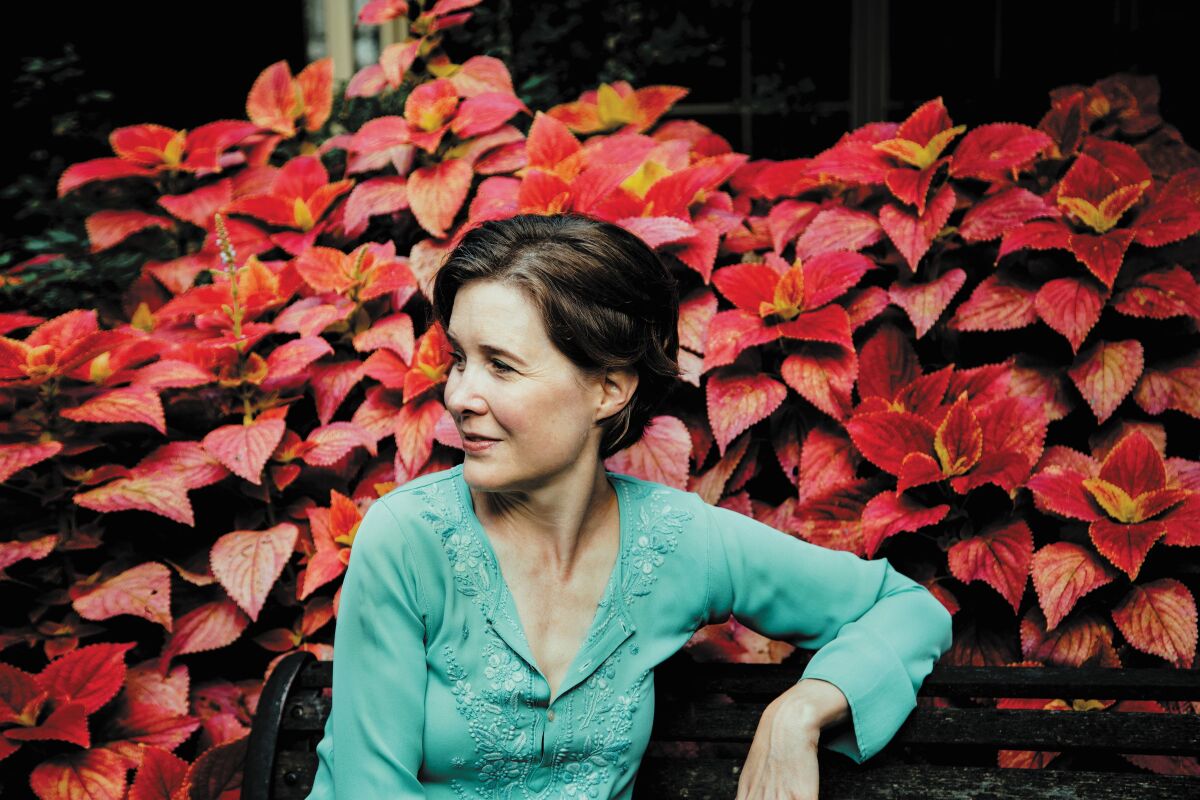 Author Ann Patchett in front of a wall of red plants.