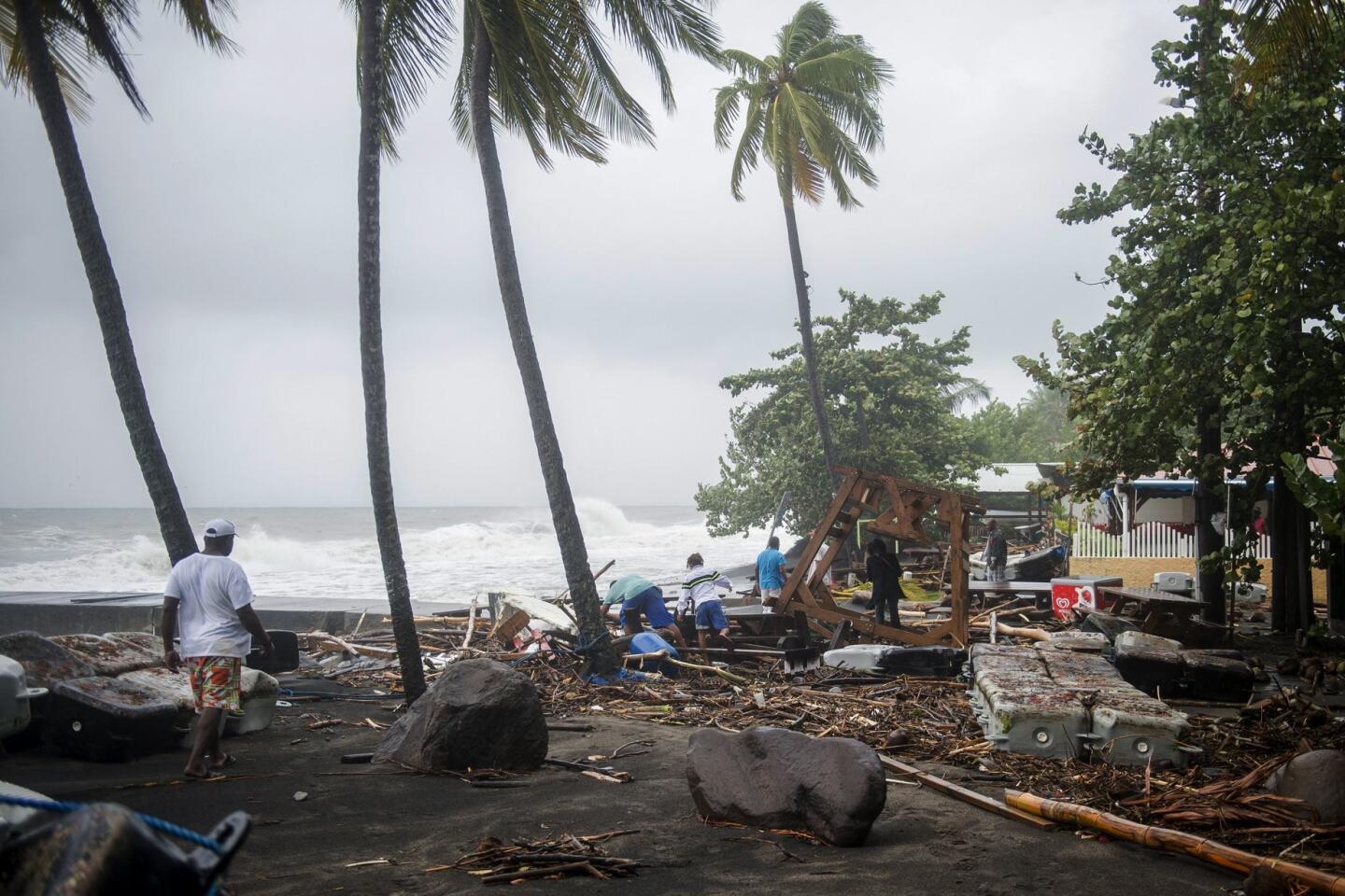 People walk amid debris of a restaurant shattered by Hurricane Maria in Le Carbet on the French Caribbean island of Martinique.