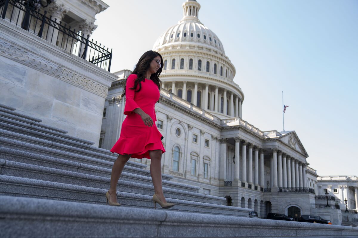A woman in a red dress walks down the broad steps of a government building.