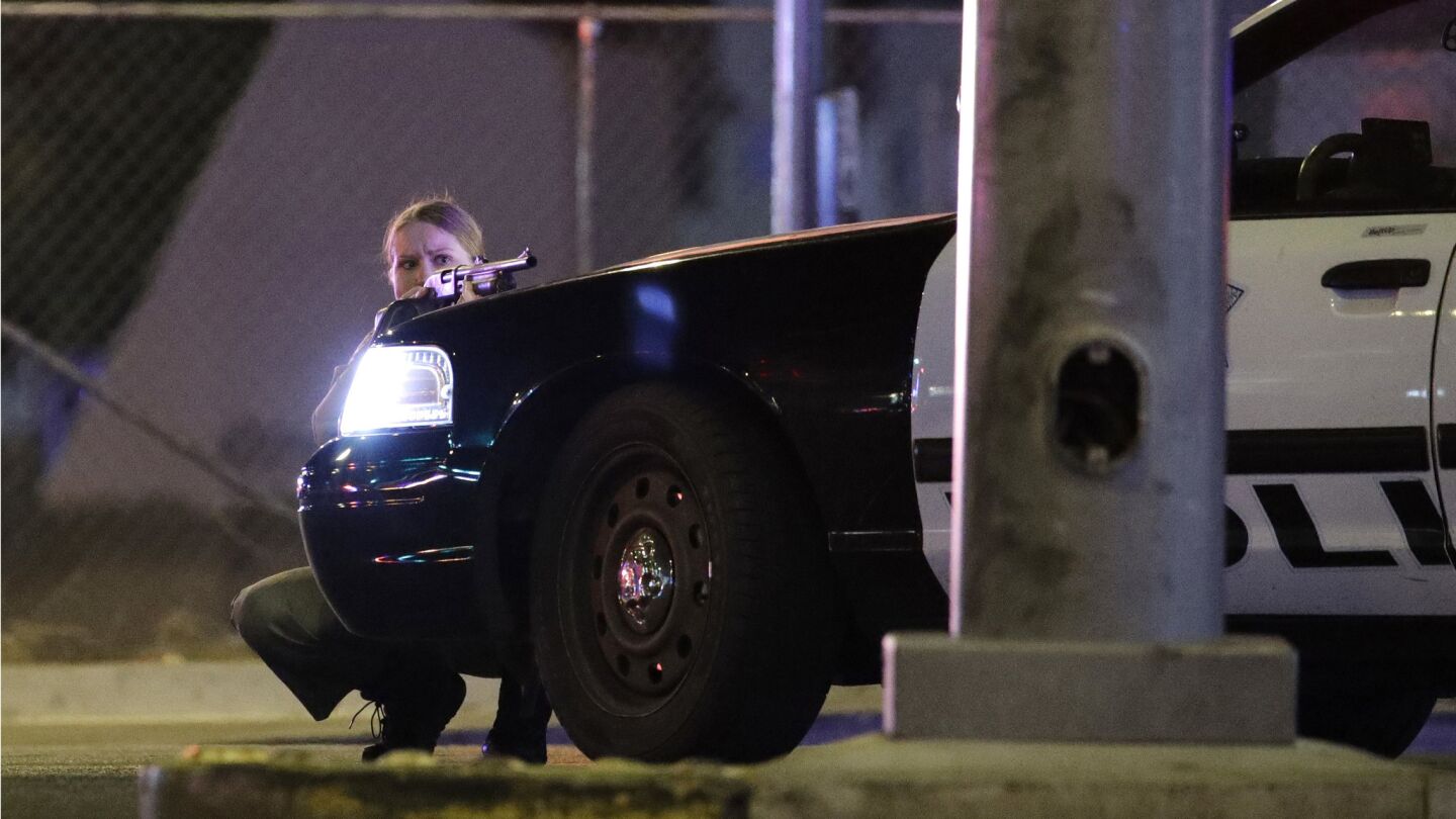 A police officer takes cover behind a police vehicle during a shooting near the Mandalay Bay Resort and Casino on the Las Vegas Strip.