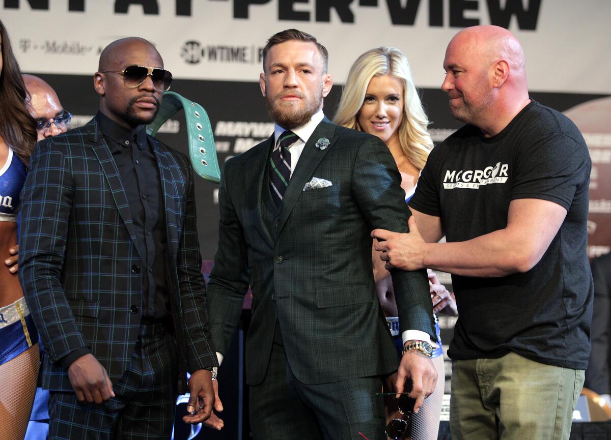 UFC president Dana White grabs Connor Mcgregor's arm as he poses with Floyd Mayweather Jr. during a news conference Aug. 23, 2017 at the MGM Grand.