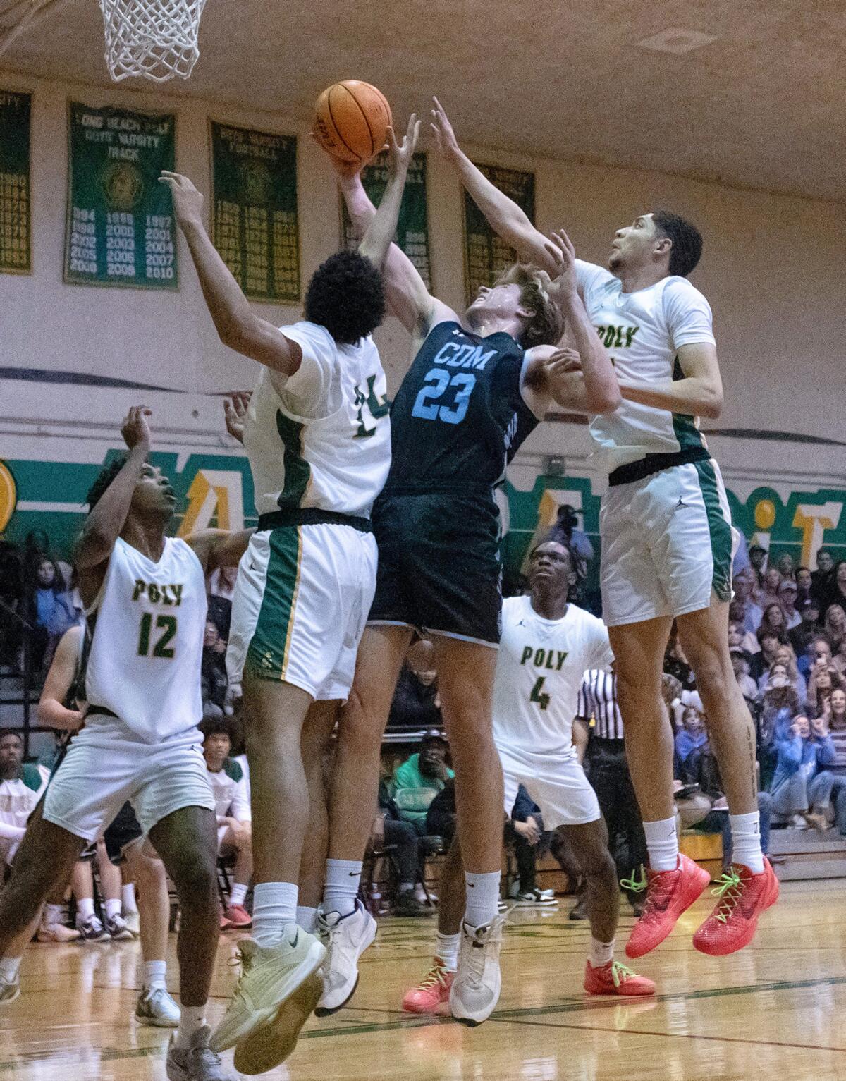 CdM junior forward Jackson Harlan battles for a rebound against two Long Beach Poly players on Friday night.