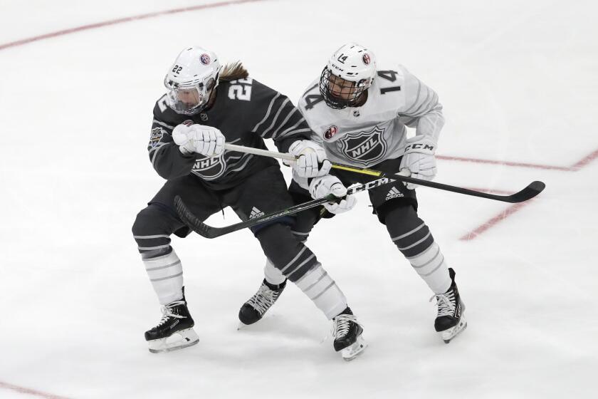United States' Kacey Bellamy (22) and Canada's Renata Fast (14) battle for the puck during the first period in the women's 3-on-3 game, part of the NHL hockey All-Star weekend, Friday, Jan. 24, 2020, in St. Louis. (AP Photo/Jeff Roberson)