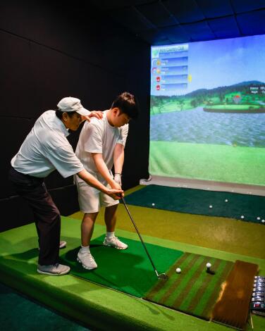 One person coaches another person on their swing at W Screen Golf in Koreatown.