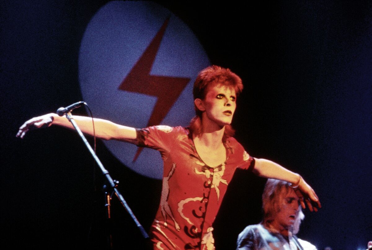 David Bowie spreads his arms on a stage 