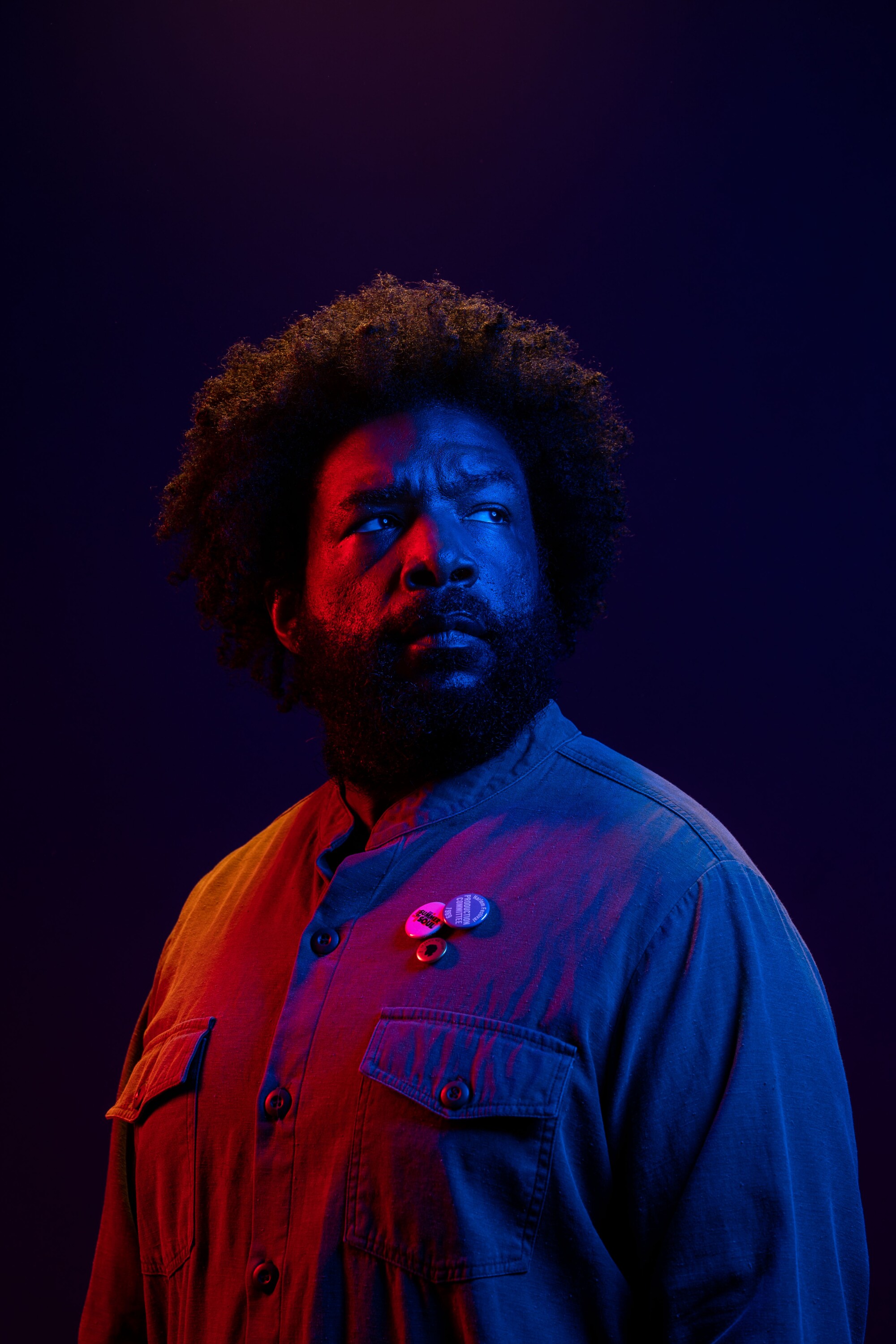 A man poses for a portrait under red and blue lighting.