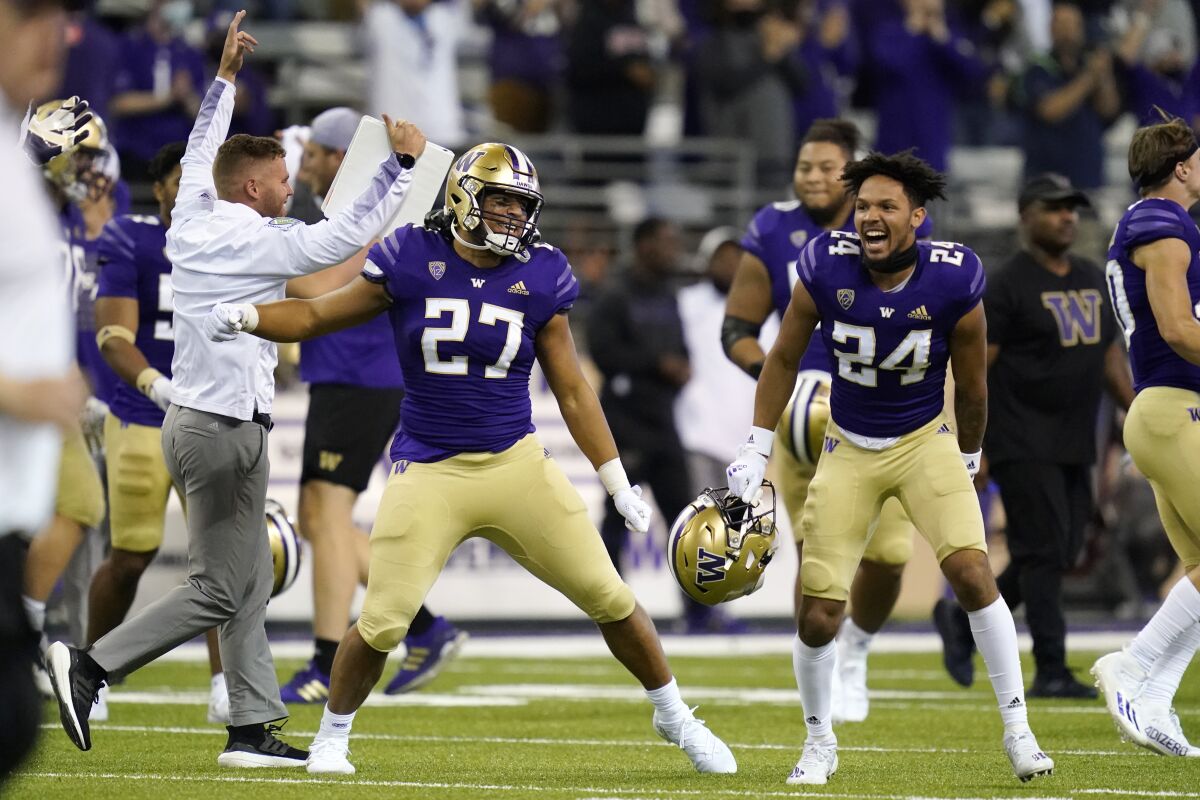 Washington players and coaches celebrate beating California on Sept. 25, 2021.