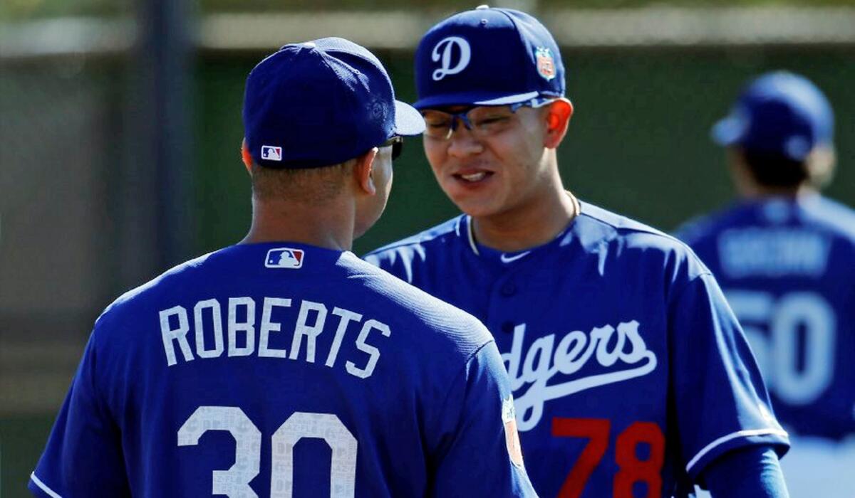 Dodgers Manager Dave Roberts talks to pitching prospect Julio Urias during a spring training workout in Glendale, Ariz on Feb. 20.