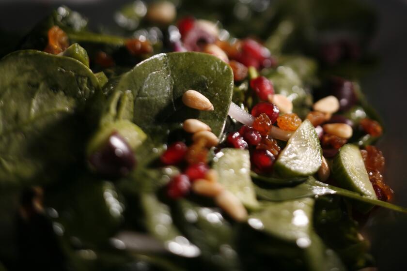 Spinach salad with olives, pomegranate seeds and pine nuts.
