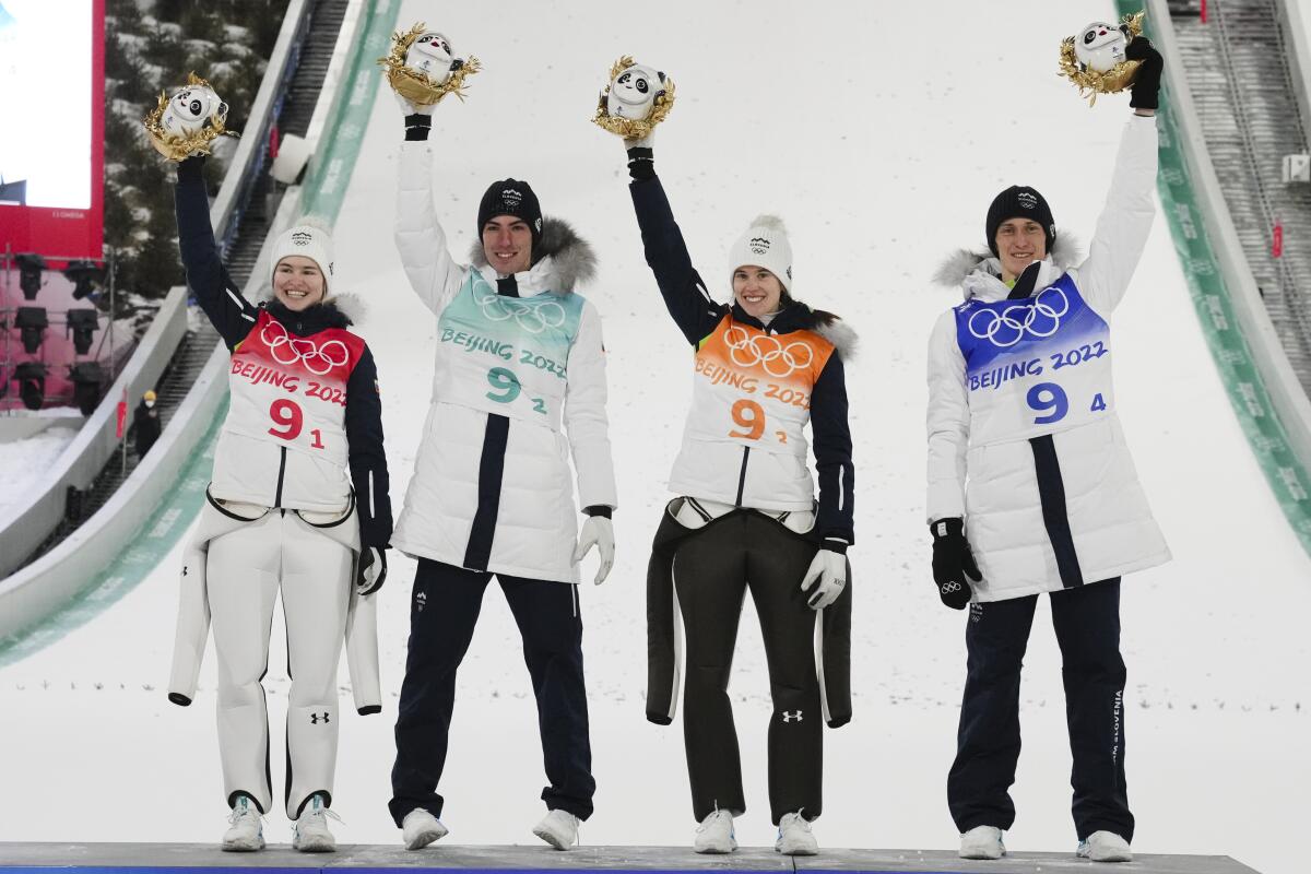 Slovenia's Nika Kriznar, Timi Zajc, Ursa Bogataj and Peter Prevc wave after winning gold.