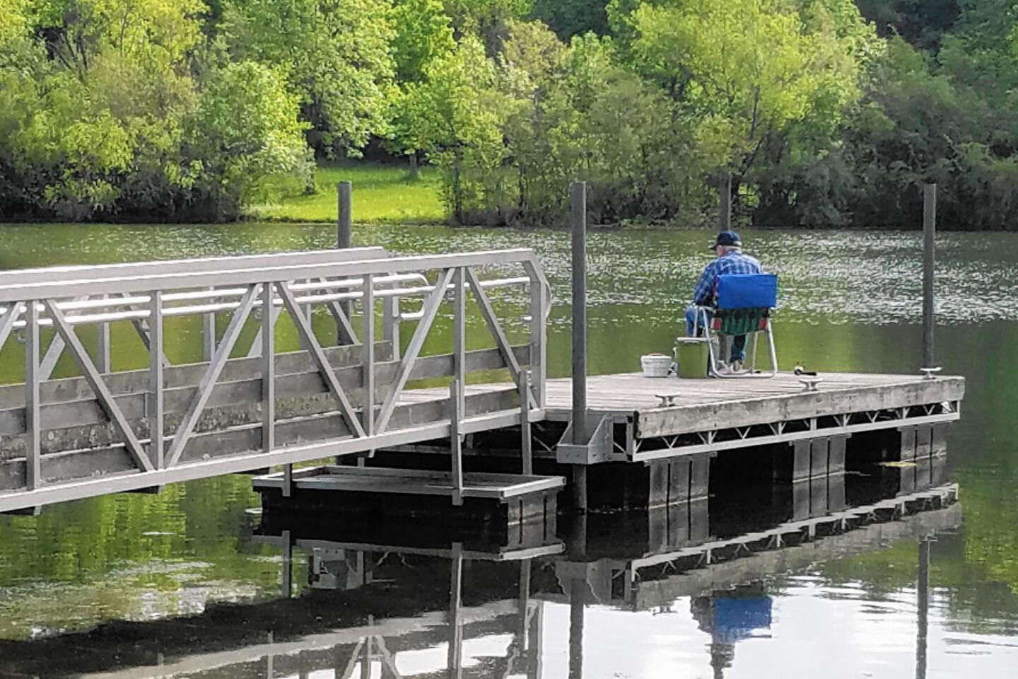 A solitary fisherman sits on the dock of the human-made lake at Beall Woods State Park near Mount Carmel in southeastern Illinois.