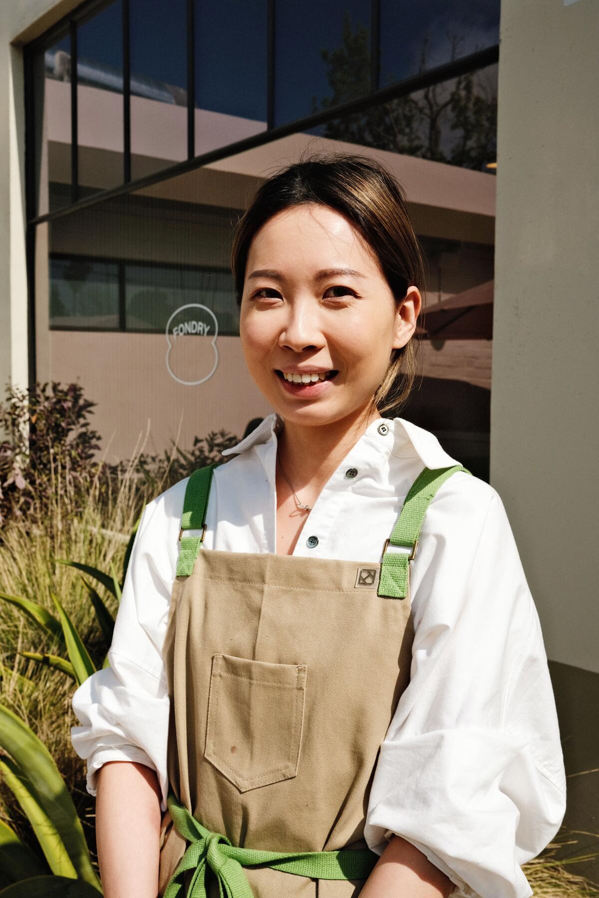 A portrait of Ivy Ku wearing an apron and standing in front of her Eagle Rock bakery, Fondry