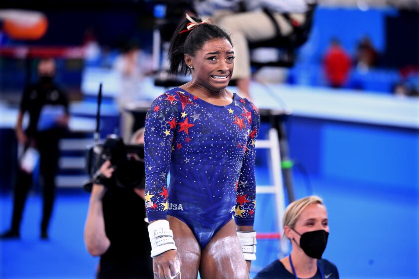 Simone Biles reacts after competing on the uneven bars at the Olympics.