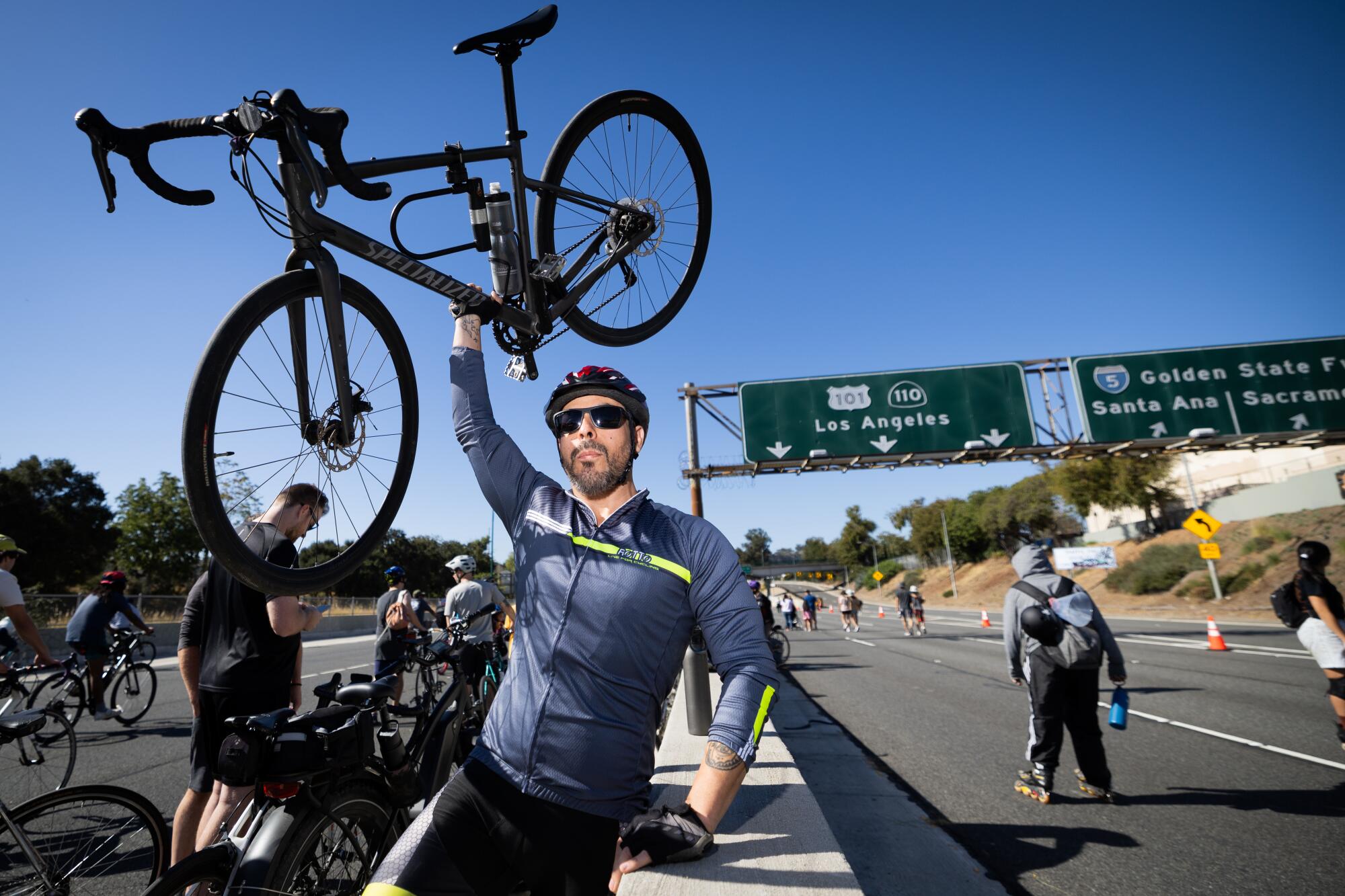 LDiego Chavez, of Wilmington, hoists his bike while taking a break in the middle of the 110 Freeway.
