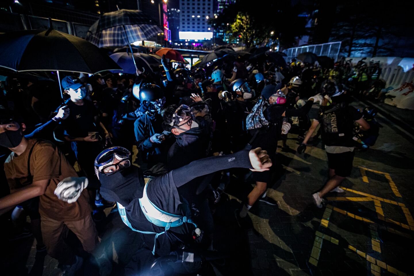 Pro-democracy demonstrators throw bricks at windows of the Central Government building while a peaceful rally commemorating the 5th umbrella movement is concurrently taking place at Tamar Park in Hong Kong.