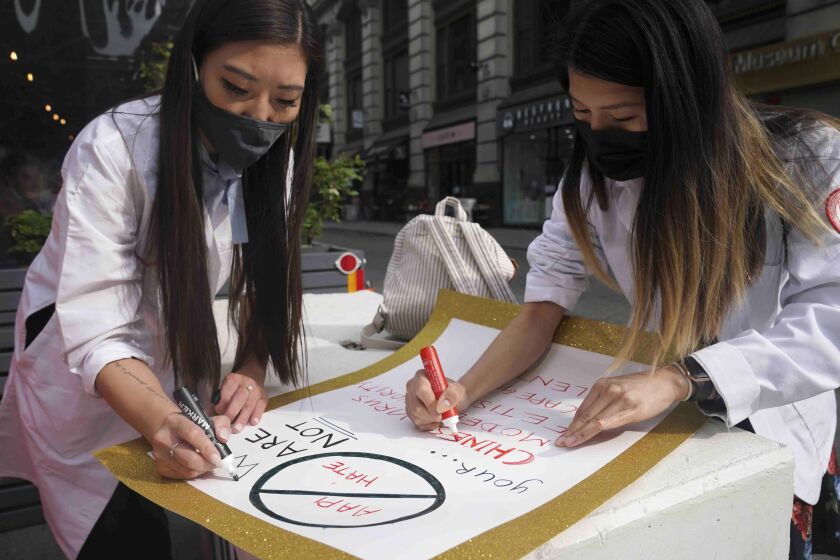 Dr. Michelle Lee, left, a radiology resident, and Ida Chen, right, a physician assistant student, prepare posters they carry at rallies protesting anti-Asian hate, Saturday April 24, 2021, in New York's Chinatown. Lee, who is Korean-born, and Chen, who is American-born Chinese, join medical professionals of Asian and Pacific Island descent who feel the anguish of being racially targeted because of the virus while toiling to keep people from dying of it. (AP Photo/Bebeto Matthews)